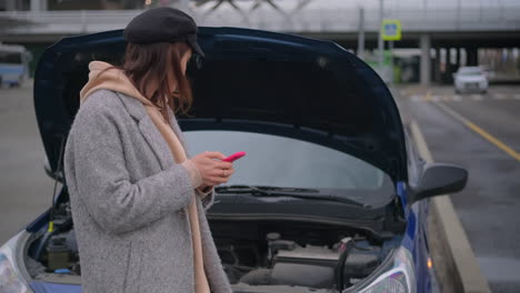 mujer con un coche averiado buscando ayuda en su teléfono
