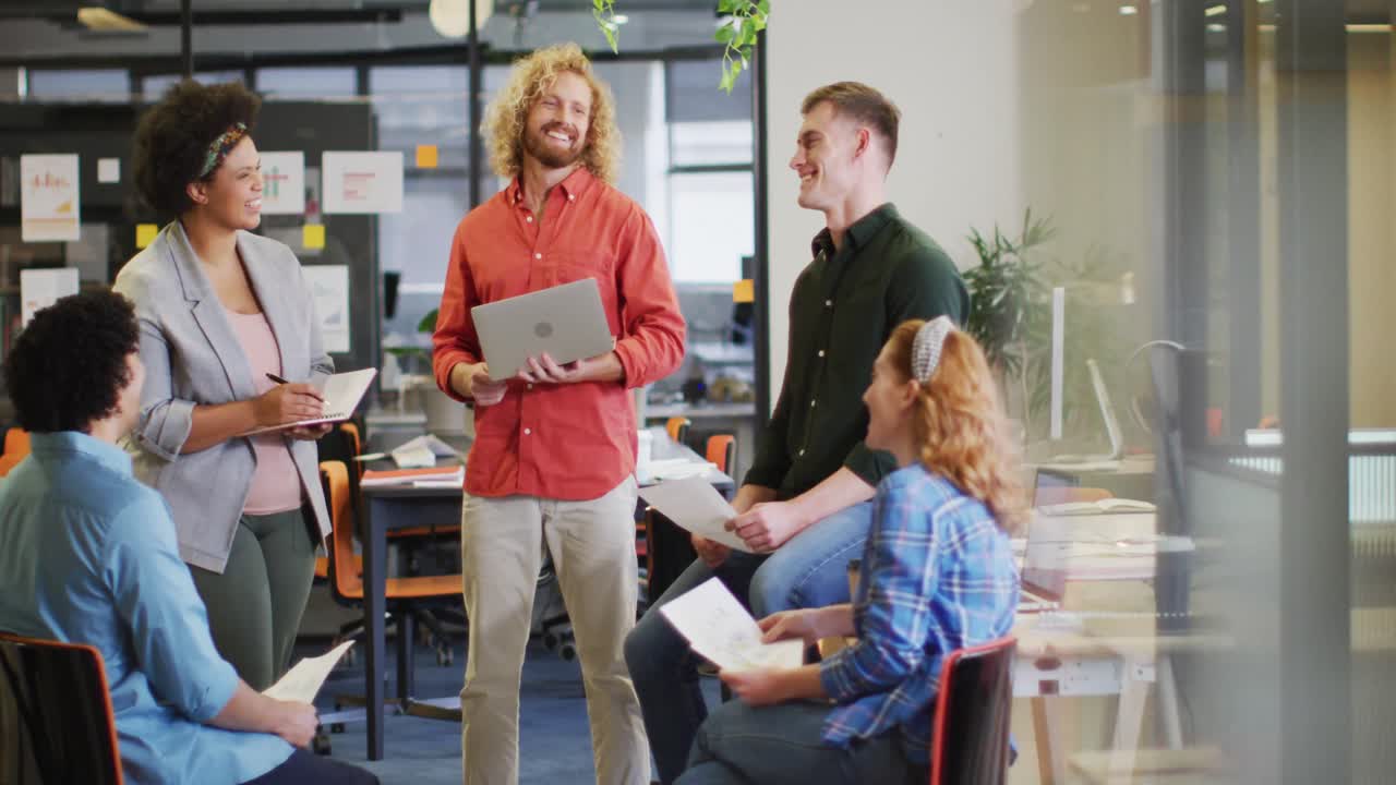 Glade mangfoldige forretningsfolk diskuterer arbejde med dokumenter på kontoret.