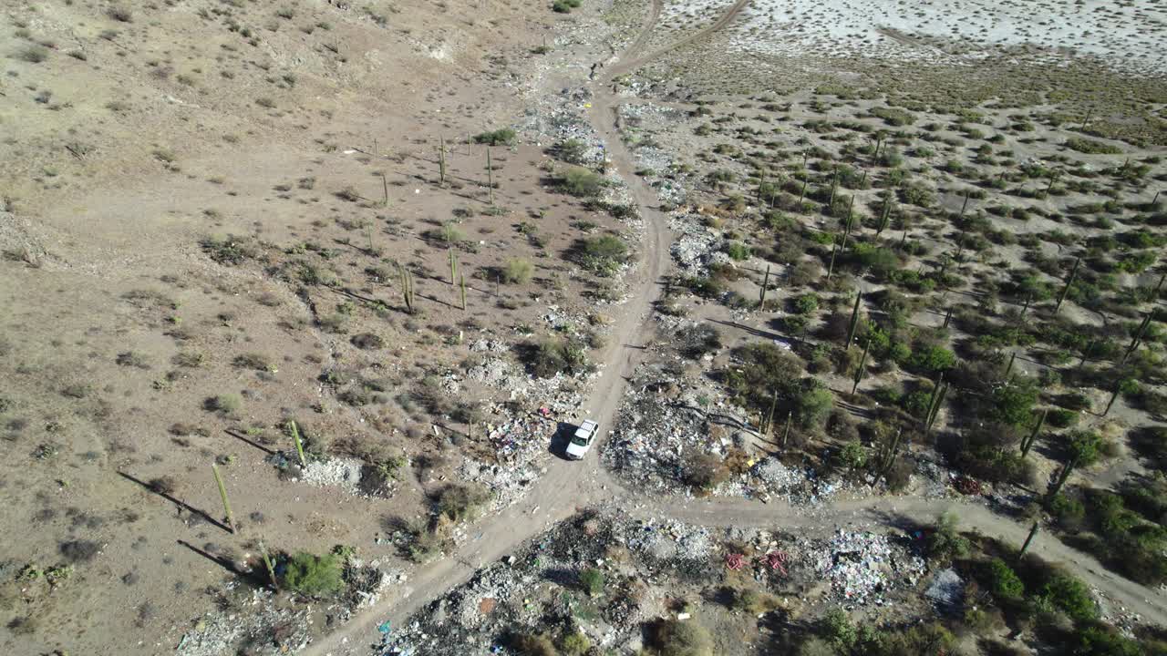 basura esparcida a lo largo de la carretera cerca de un vehículo blanco en mulege, baja california sur, méxico - avión no tripulado volando hacia adelante