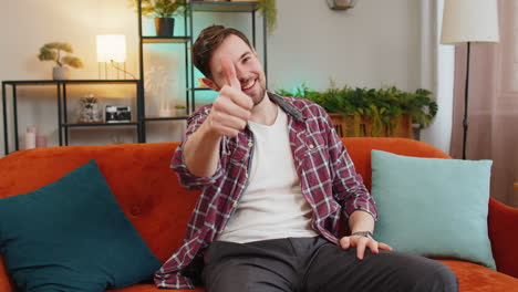 happy man looking approvingly at camera showing double thumbs up like sign positive feedback at home