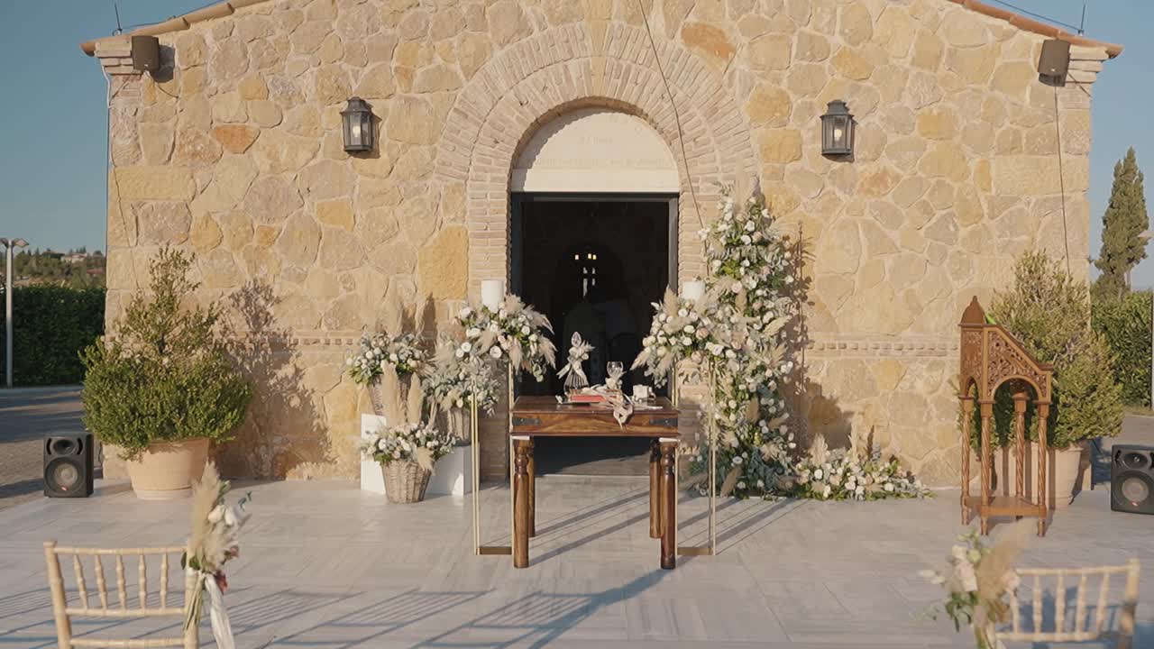 Rustic outdoor wedding setup at stone church, peaceful, sunny atmosphere