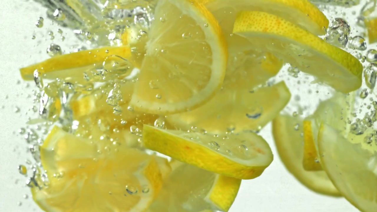 Fresh Lemon Slices Falling and Floating in Clear Water