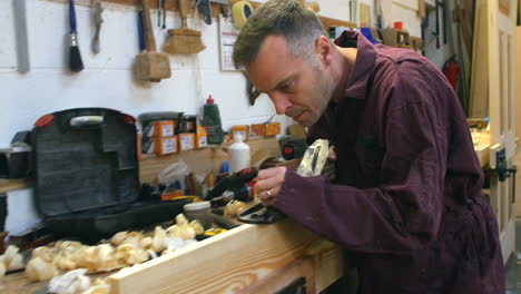 carpenter planing wood in workshop