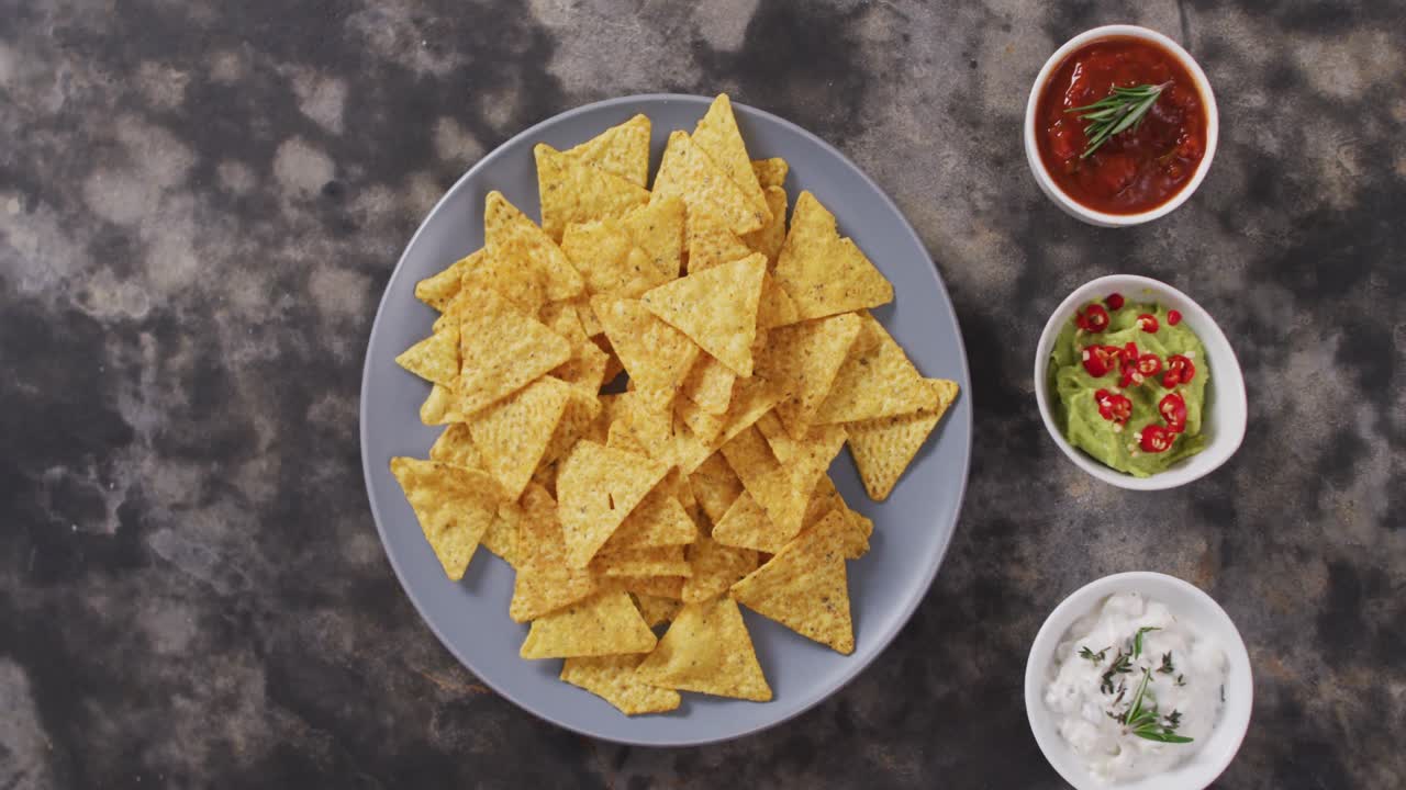 cerca de nachos en un plato y salsas en superficie negra