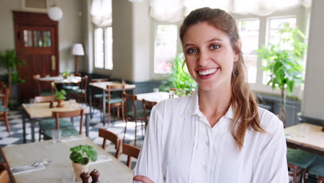 portrait of waitress standing in empty restaurant before start of service