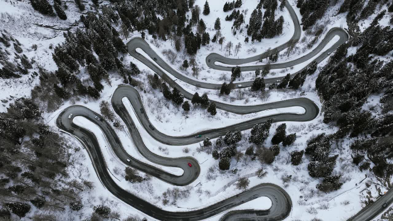 Aerial View of Winding Road Through Snow Covered Maloja Pass in Switzerland During Winter Featuring Cars Driving Through the Mountain Landscape