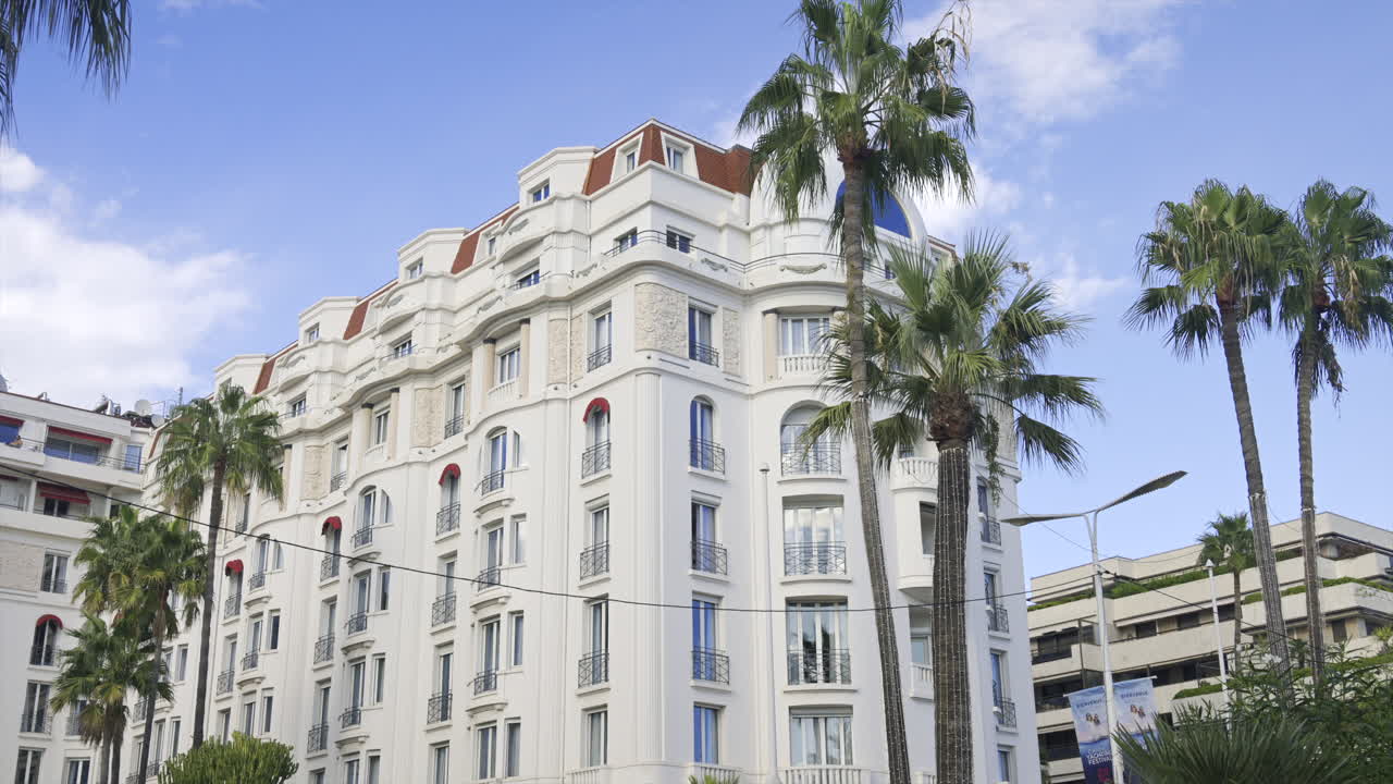 Cannes, France - June 22, 2025: Side view of the Hotel Barriere Le Majestic surrounded by palm tress in daylight