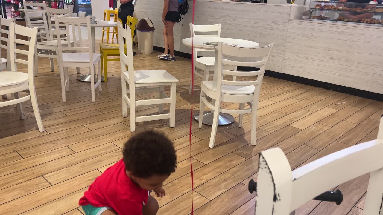 Scena di gioia: un bambino sorridente e felice che gioca con un palloncino a elio in una caffetteria