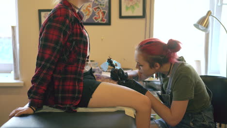 tattoo artist working on a client's leg