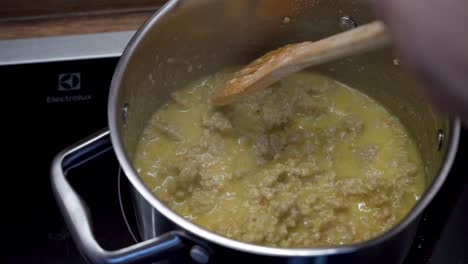 close up shot of hand stirring minced meat in a pot