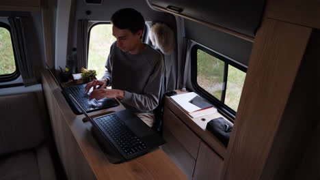 man working on laptops inside a camper van
