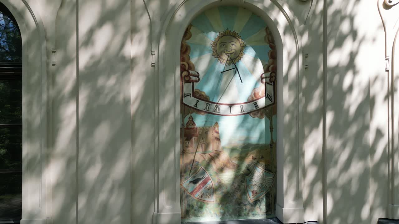 A picture in the window of the facade of an old castle in Zywiec - sundial