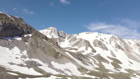 disparo de un dron de gran angular que pasa junto a un excursionista con la cordillera del gran sasso durante un día de primavera ubicado en la región de abruzzo en italia