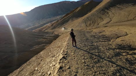 Drone-pilot-with-FPV-viewer-controlling-DJI-Avata-quadcopter-with-wireless-remote-control-in-desert-zone,-Factory-Butte-in-Utah,-USA