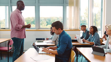 Tutor-Masculino-De-Pie-Para-Enseñar-A-Clase-De-Estudiantes-Maduros