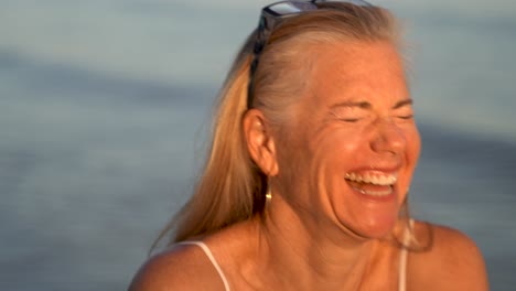 closeup of mature blonde woman with gray hair playing with her hair and looking old in granny glasses and laughing