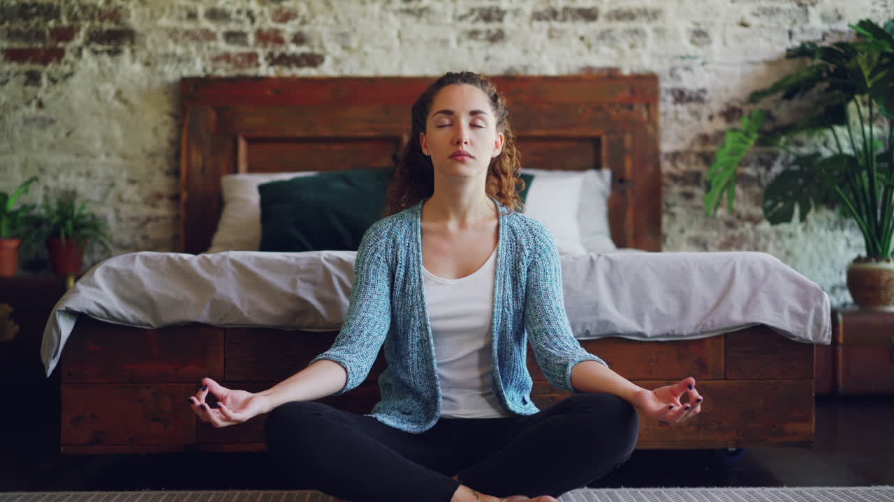 una mujer meditando en su dormitorio.