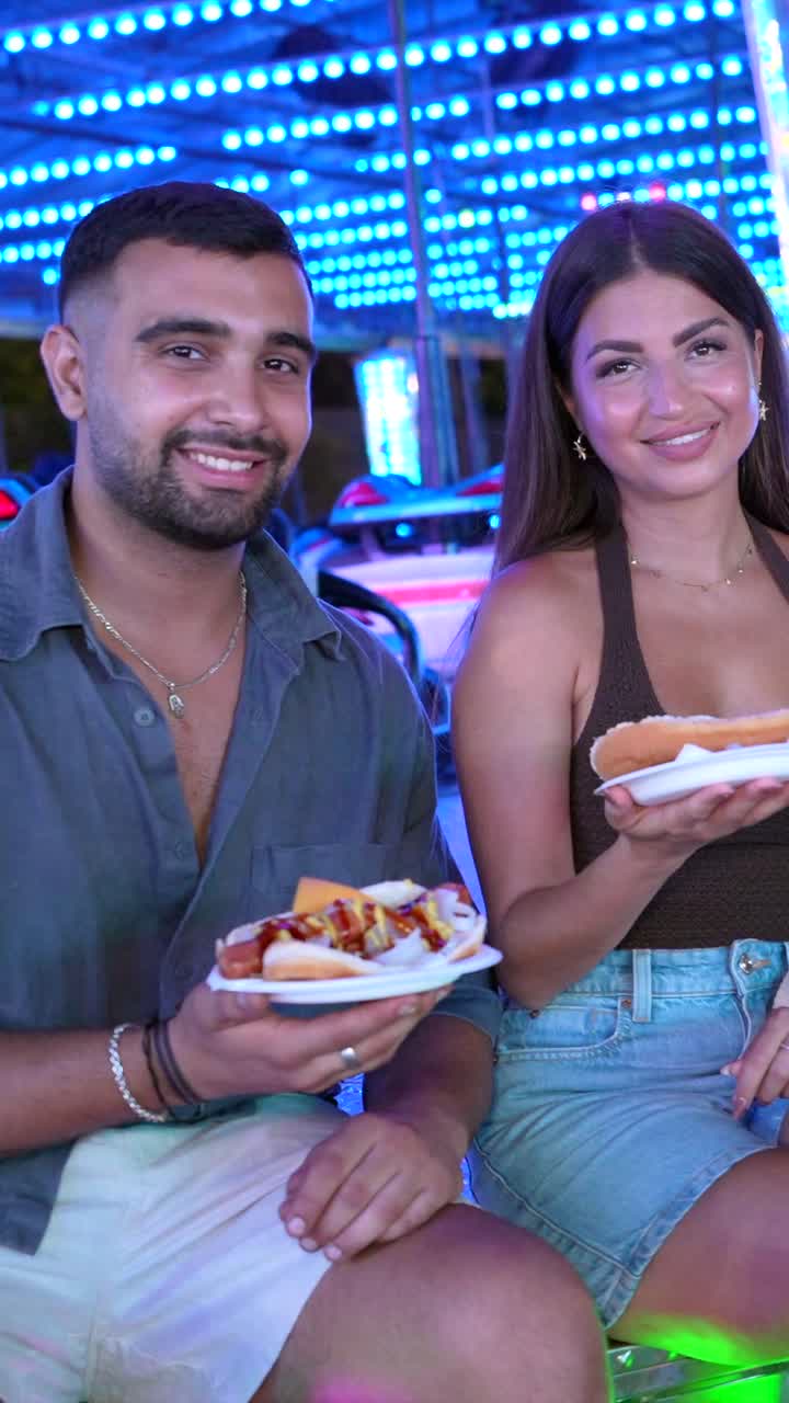 People eating hot dogs at a fair