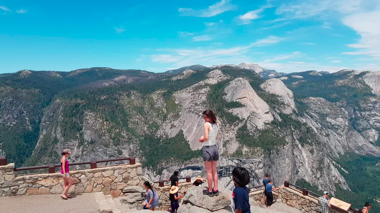 Panorama shot of view from Glacier Point with tourists admiring the view overlooking Half Dome in Yosemite National Park, California, United States