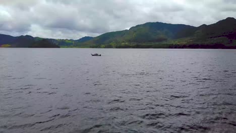 Lancha-En-Un-Lago-Rodeado-De-Montañas,-Empuje-Aéreo-Bajo