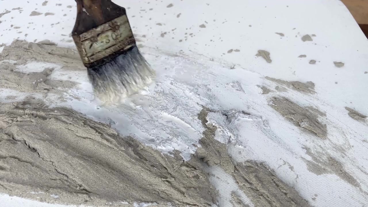 Primo piano statico in 4K di un pennello che dipinge di bianco un'opera d'arte murale in cemento testurizzato. Progetto fai-da-te minimalista per l'arredamento di casa e processo creativo.