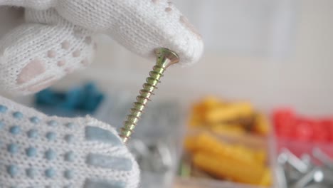 close-up of a hand in gloves holding a screw