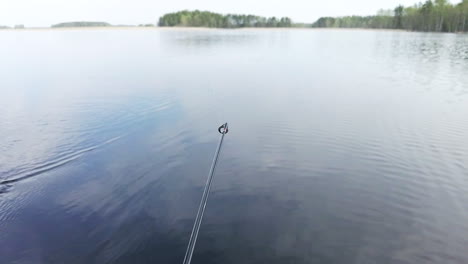 Slowmotion-shot-of-swaying-tip-of-a-fishing-pole-while-trolling-on-a-calm-lake
