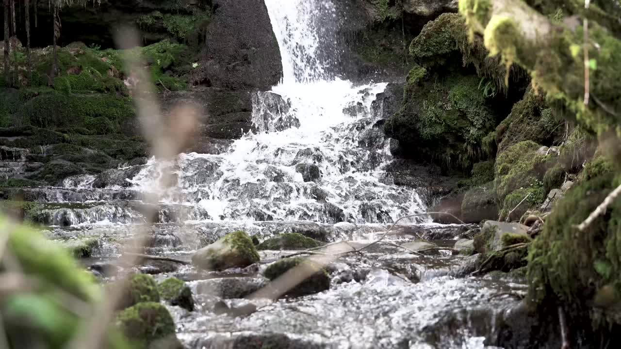 4K, long shot of small waterfall flowing over rocks in forest, South Wales, UK