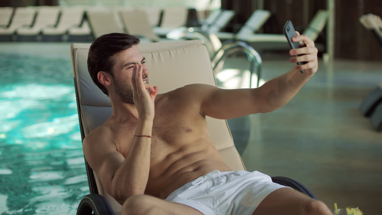 hombre guapo haciendo autorretrato en el teléfono móvil al lado de la piscina