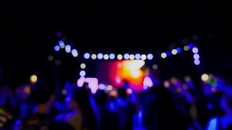 4k : abstract background blurred people enjoy concert or outdoor activity in winter. they are waving hands in front of bokeh colourful  live music or performance stage. nighttime