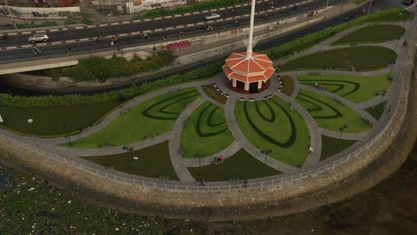 park designed with lotus flower pattern, saigon river, traffic bridge, canal and main road drone shot orbiting central flagpole