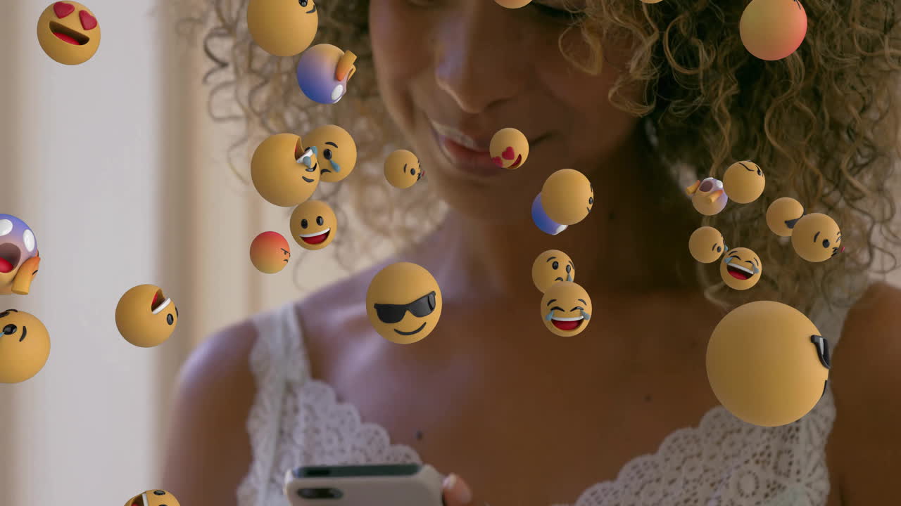 female marketer using smartphone in studio, viewing floating 3D emoji spheres for social media