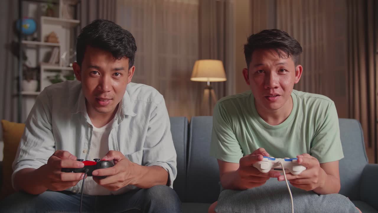 Asian Friends With Joystick Playing Video Games And Celebrating Victory At Home