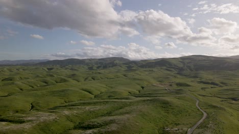 El-Dron-Se-Desliza-Hacia-Los-Lados,-Mostrando-El-Impresionante-Paralaje-De-Las-Laderas-Cubiertas-De-Hierba-Que-Descienden-De-Una-Montaña-Bajo-Una-Espléndida-Puesta-De-Sol