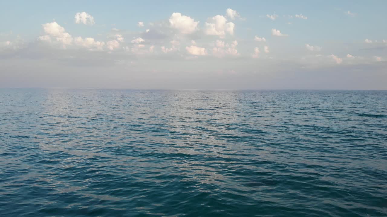 video de drones a baja altitud sobre el mar tranquilo cielo azul nubes de fondo verano soleado