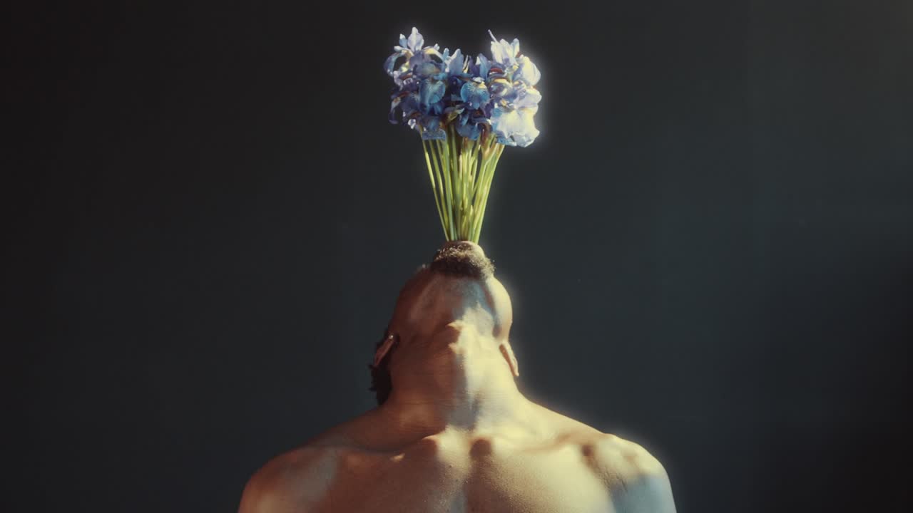 Uomo che inclina la testa all'indietro con fiori blu che gli crescono dalla bocca