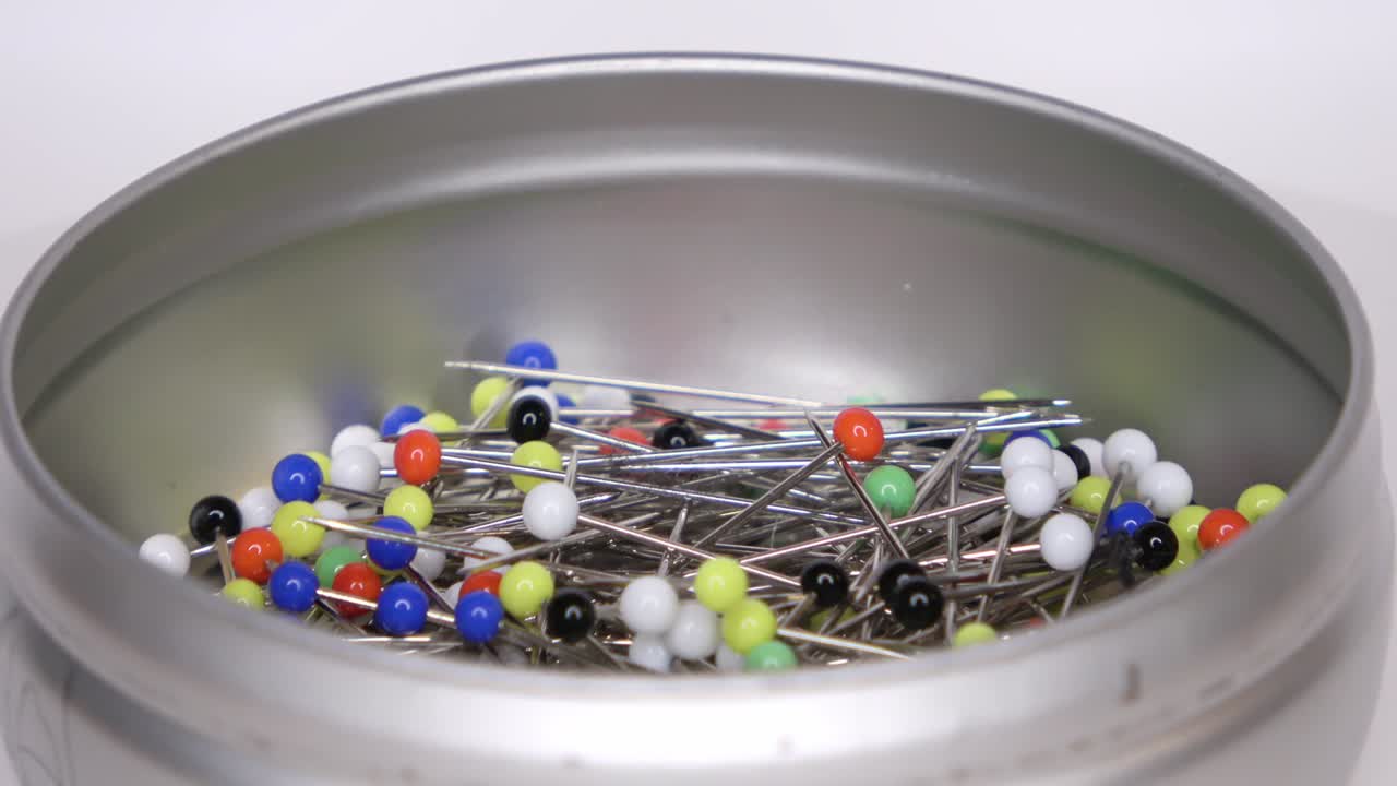 회전하는 색 배경에 다채로운 유리 머리를 가진 많은 핀의 루프 영상을 촬영할 수 있습니다.