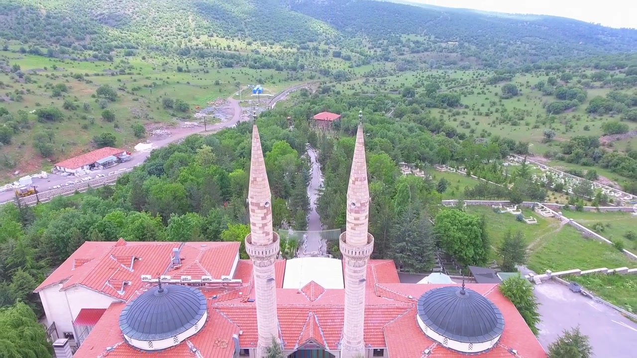 Yeşil bir manzara içinde çift minareli bir caminin havadan görünümü