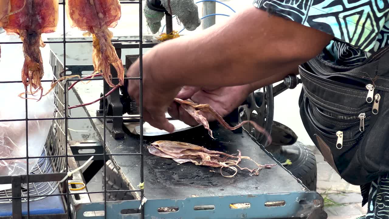 manos procesando calamar en un puesto callejero