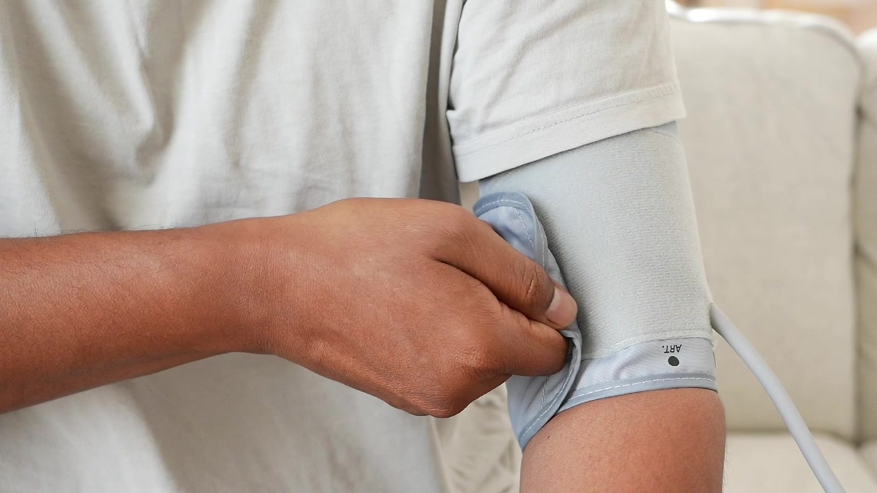 Persona che regola il bracciale del misuratore di pressione sul braccio