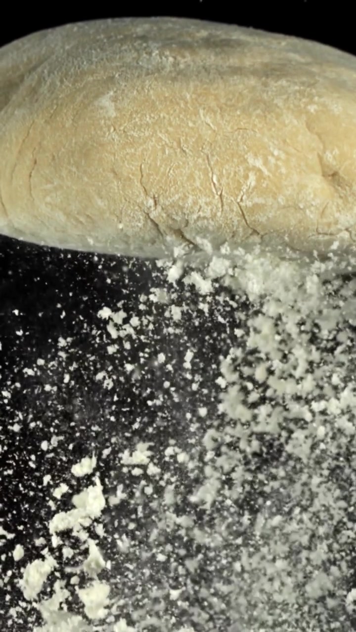 Close-up van rauw deeg met vallend meel in slow motion