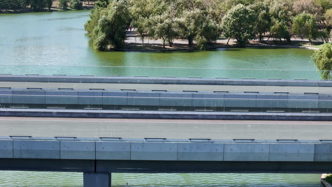 Aerial View of Tineretului Park on a Sunny Day, with a Bridge Spanning a Small Lake Surrounded by Greenery, Bucharest, Romania