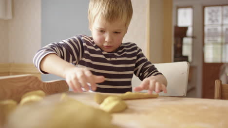 niño en la cocina rodando la masa para hornear los tradicionales panes de azafrán de navidad suecos