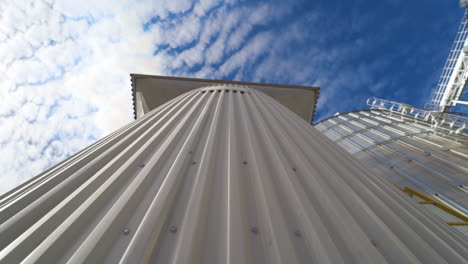 metal construction on the modern factory. storage tanks for processing grains on sky background. smoke releasing from industry into the air. close-up. motion camera top down.