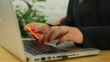 primer plano de una mujer irreconocible pagando en línea usando una tarjeta de crédito y una computadora portátil