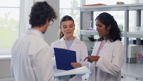 International-Group-of-Scientists-in-Laboratory.science-research,-work-and-people-concept-international-group-of-happy-scientists-with-clipboards-discussing-report-in-laboratory