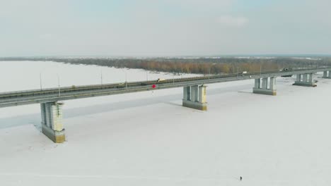 An-Sonnigen-Tagen-Fahren-Autos-Entlang-Der-Langen-Brücke-über-Den-Zugefrorenen-Fluss