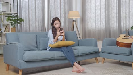 woman using smartphone on sofa in a living room