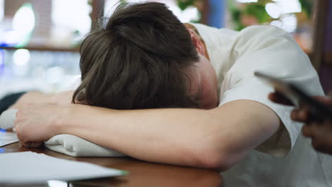 close up of european boy resting head on wooden table eyes closed conveying peaceful nap mood school environment soft light gentle focus capturing candid youthful rest moment with soft sunrise glows