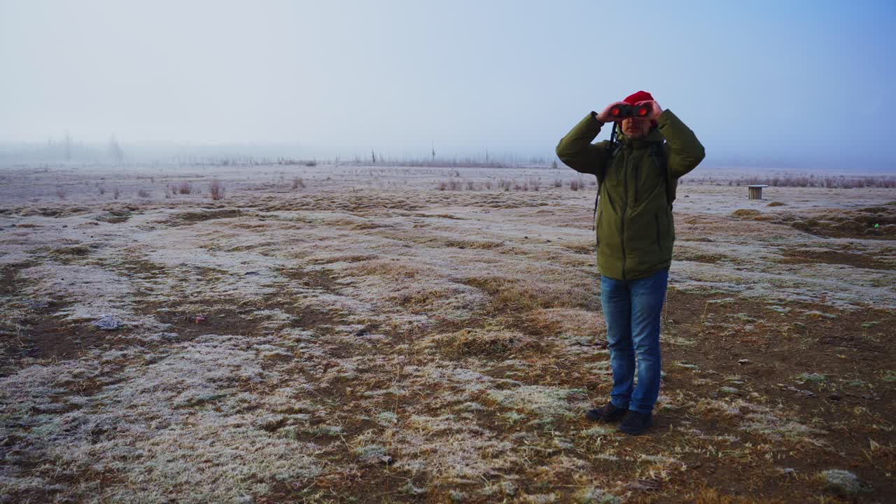 Uomo con binocolo in un paesaggio invernale